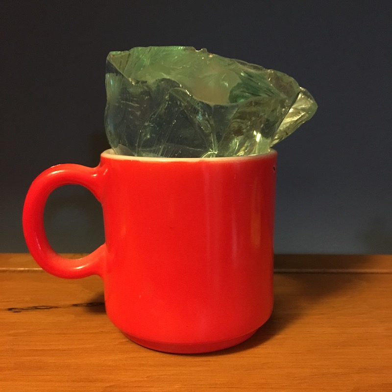 photo of a red glass mug and a large shard of glass